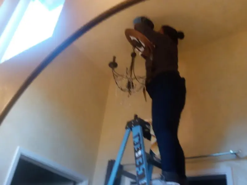 Electrician installing a chandelier in a Conneaut residence